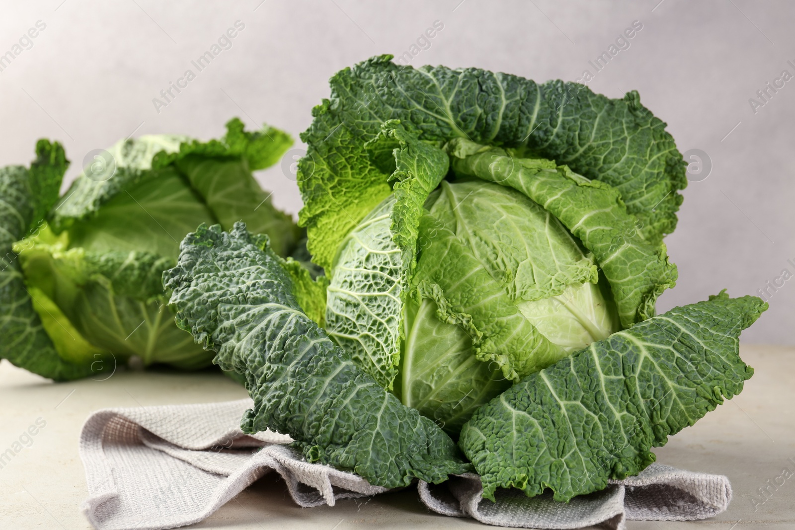 Photo of Fresh Savoy cabbages on light grey table, closeup
