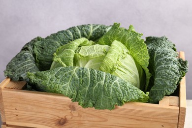 Photo of Fresh Savoy cabbage in wooden crate on grey background, closeup