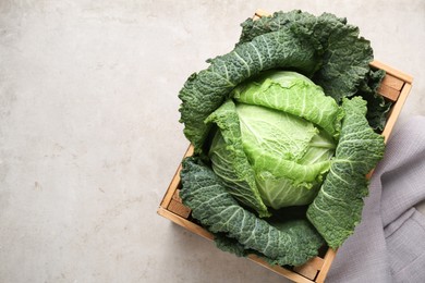 Photo of Fresh Savoy cabbage in wooden crate on light grey table, top view. Space for text