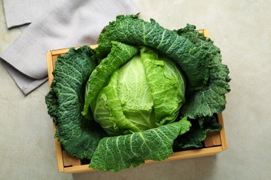 Photo of Fresh Savoy cabbage in wooden crate on light grey table, top view