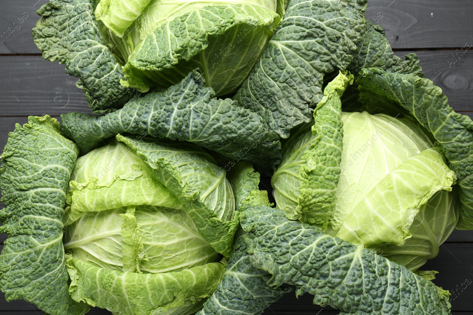 Photo of Fresh Savoy cabbages on black wooden table, flat lay