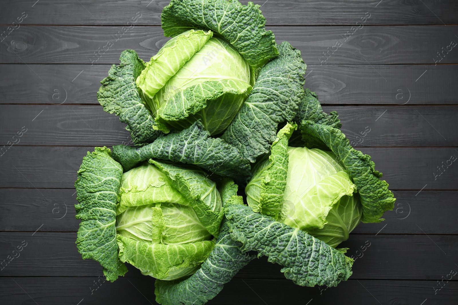 Photo of Fresh Savoy cabbages on black wooden table, flat lay
