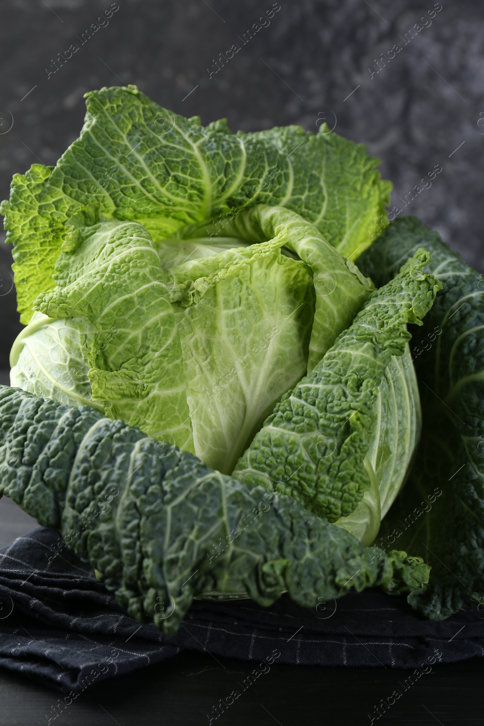 Photo of Fresh ripe Savoy cabbage on black wooden table, closeup