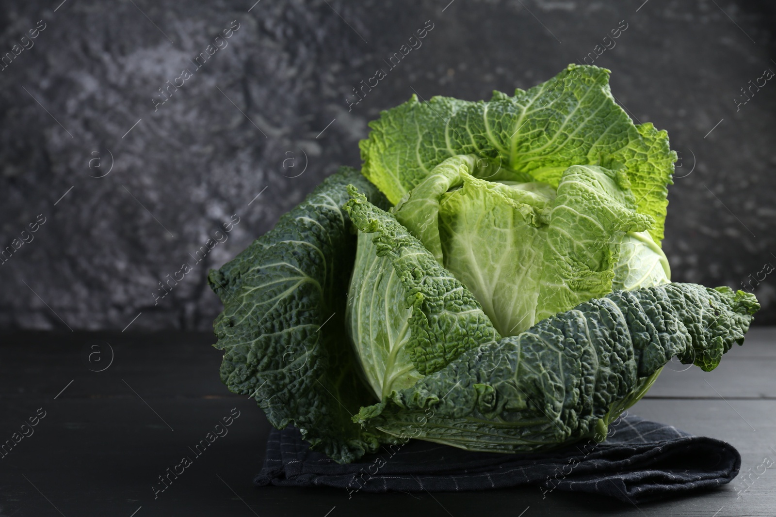 Photo of Fresh ripe Savoy cabbage on black wooden table, closeup