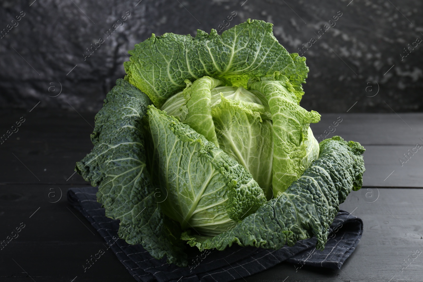 Photo of Fresh ripe Savoy cabbage on black wooden table, closeup
