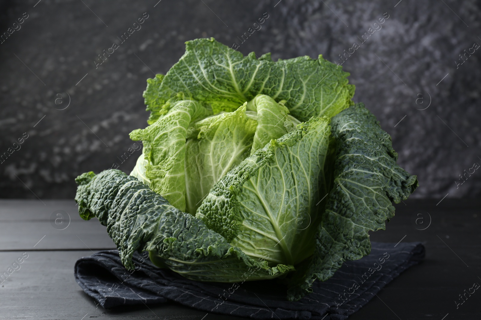 Photo of Fresh ripe Savoy cabbage on black wooden table, closeup