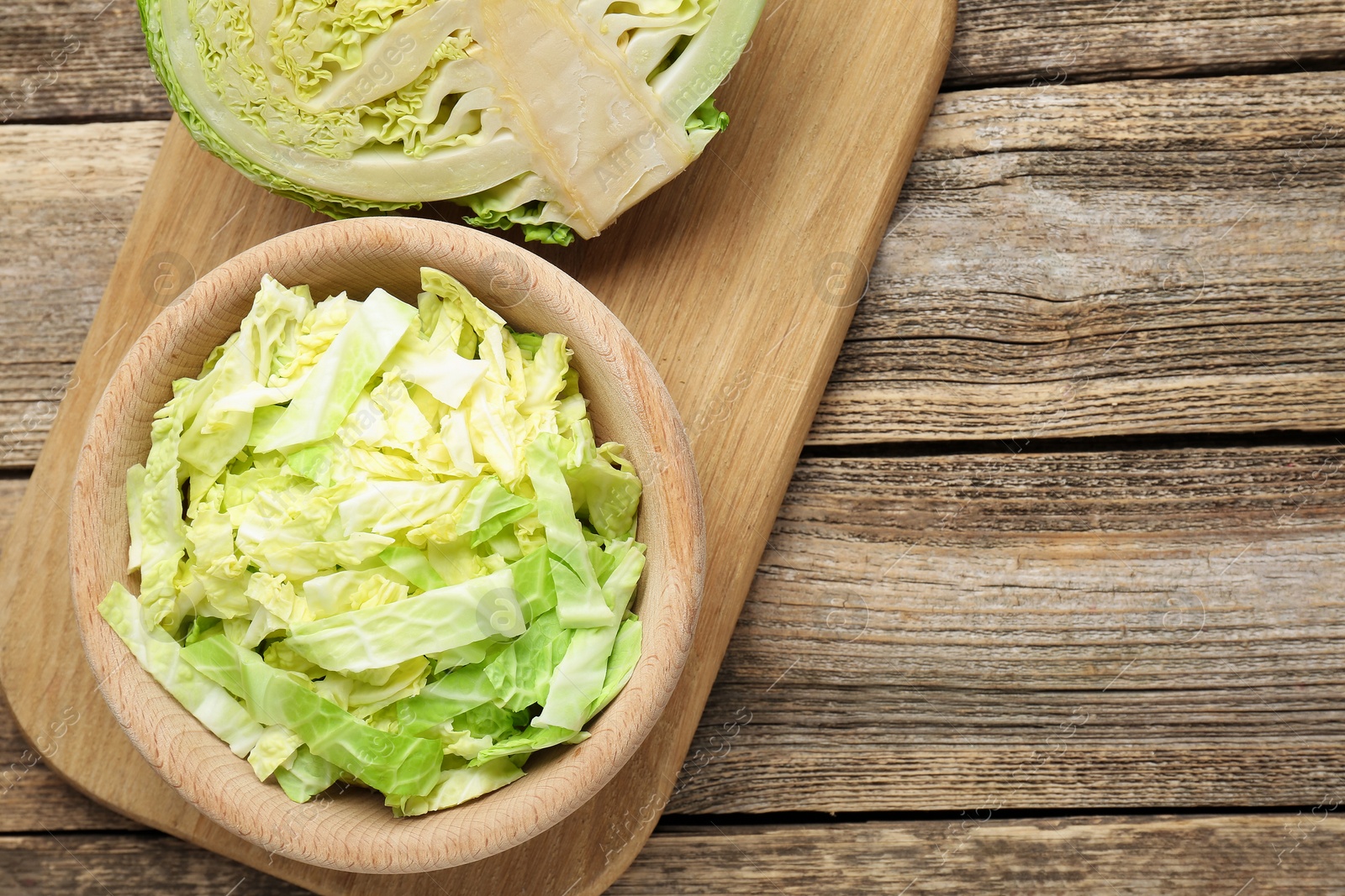 Photo of Cut fresh Savoy cabbage on wooden table, flat lay. Space for text