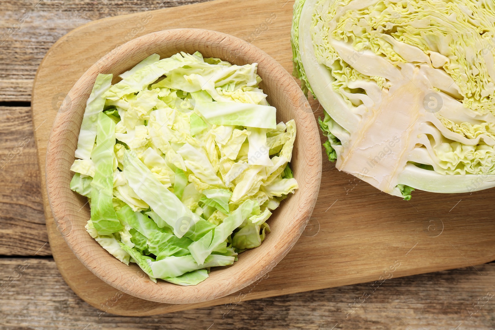 Photo of Cut fresh Savoy cabbage on wooden table, flat lay
