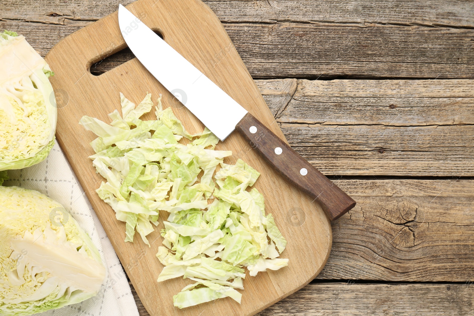 Photo of Cut fresh Savoy cabbage and knife on wooden table, flat lay. Space for text