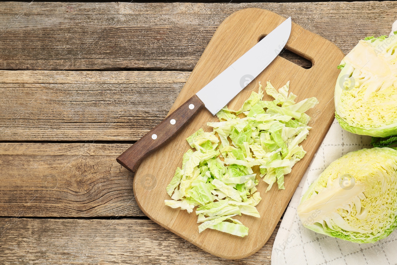 Photo of Cut fresh Savoy cabbage and knife on wooden table, flat lay. Space for text