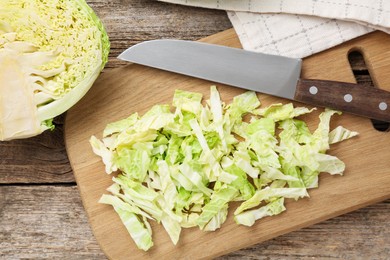 Photo of Cut fresh Savoy cabbage and knife on wooden table, flat lay