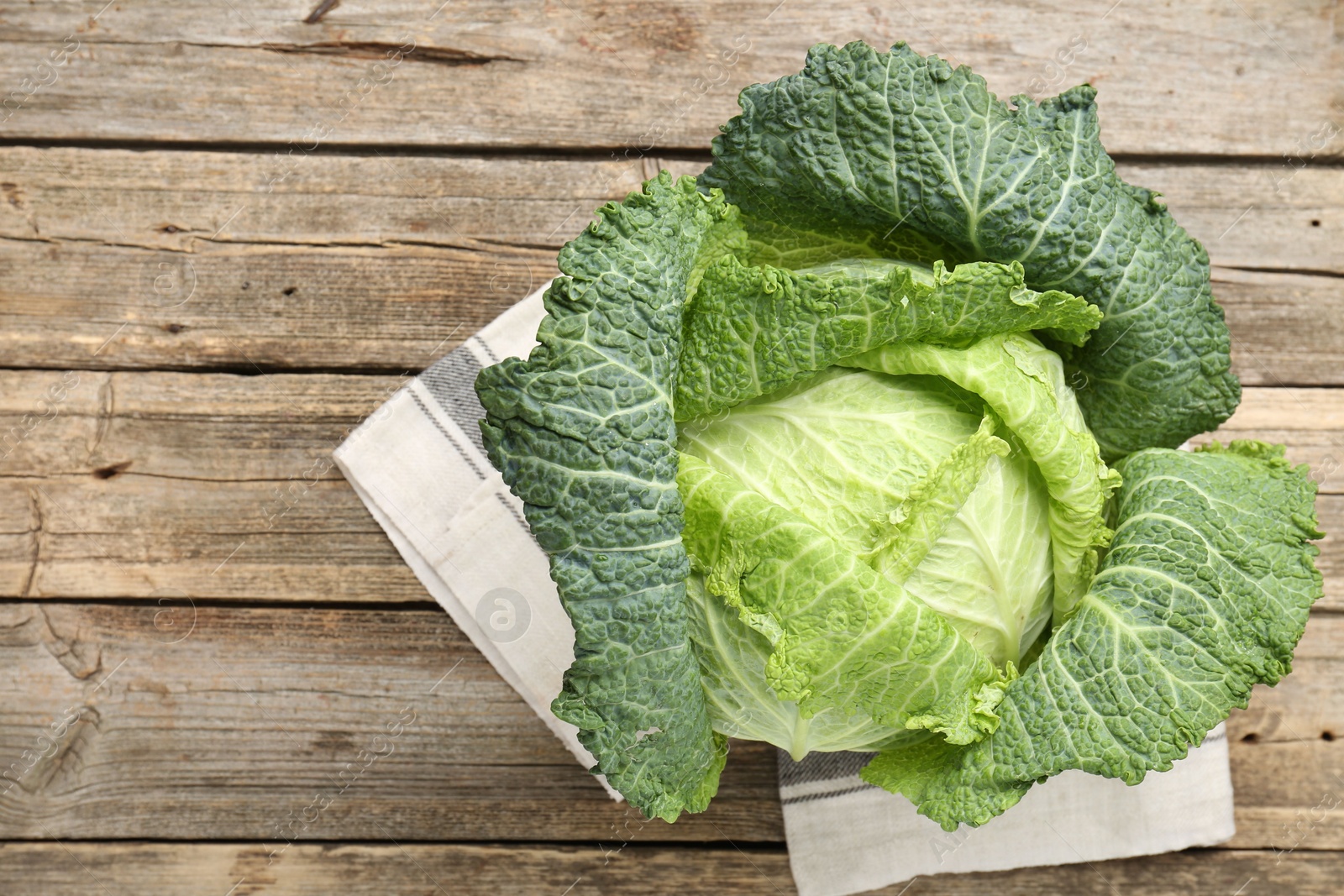 Photo of Fresh ripe Savoy cabbage on wooden table, top view. Space for text
