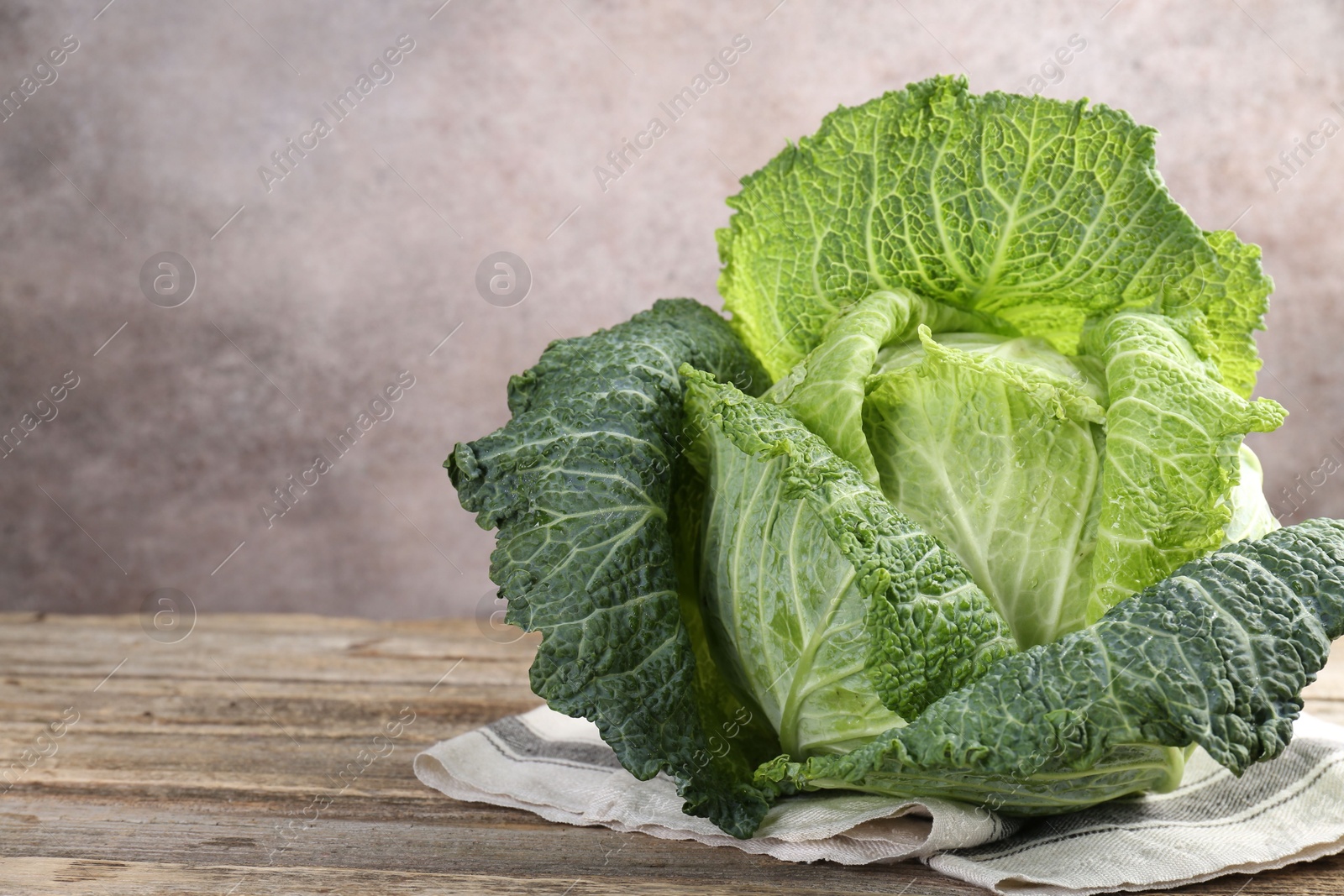 Photo of Fresh ripe Savoy cabbage on wooden table, closeup. Space for text