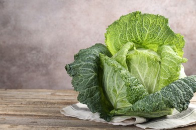 Photo of Fresh ripe Savoy cabbage on wooden table, closeup. Space for text