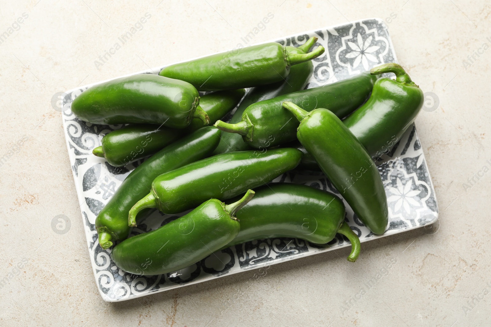 Photo of Fresh jalapeno peppers on light textured table, top view