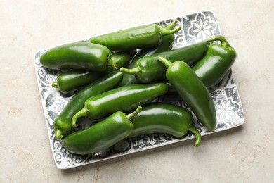 Photo of Fresh jalapeno peppers on light textured table, top view