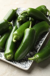 Photo of Fresh jalapeno peppers on light textured table, closeup