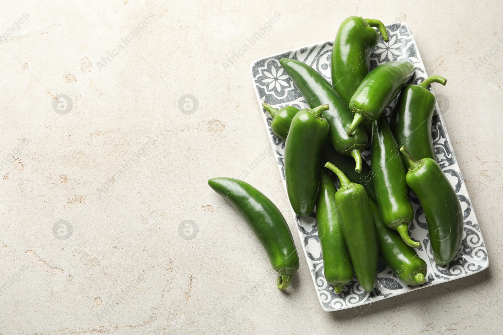 Photo of Fresh jalapeno peppers on light textured table, top view. Space for text