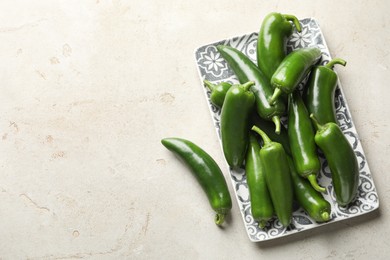 Photo of Fresh jalapeno peppers on light textured table, top view. Space for text