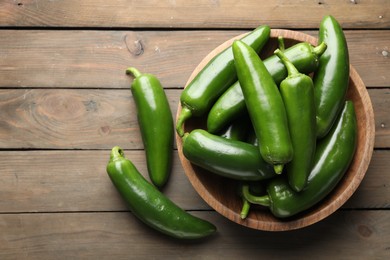 Photo of Fresh jalapeno peppers on wooden table, top view. Space for text