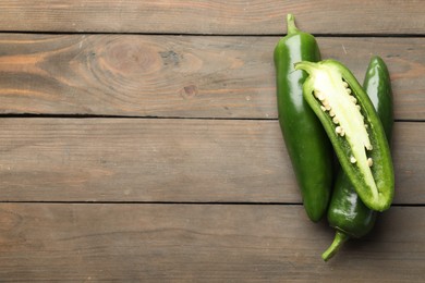 Photo of Fresh jalapeno peppers on wooden table, top view. Space for text