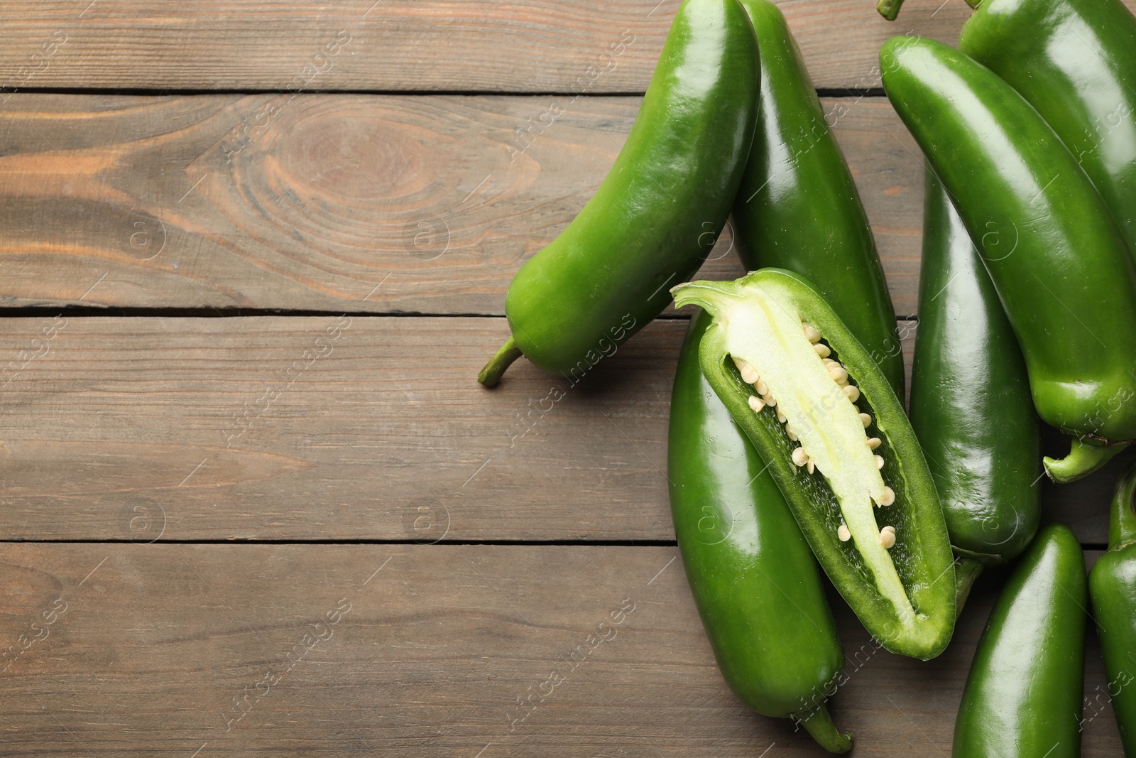Photo of Fresh jalapeno peppers on wooden table, closeup. Space for text