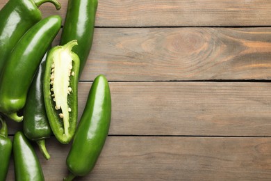 Photo of Fresh jalapeno peppers on wooden table, top view. Space for text