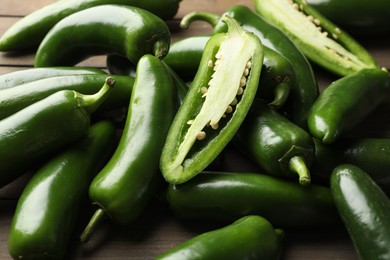 Photo of Fresh jalapeno peppers on wooden table, closeup