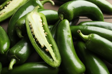 Photo of Fresh jalapeno peppers on table, closeup. Whole and cut