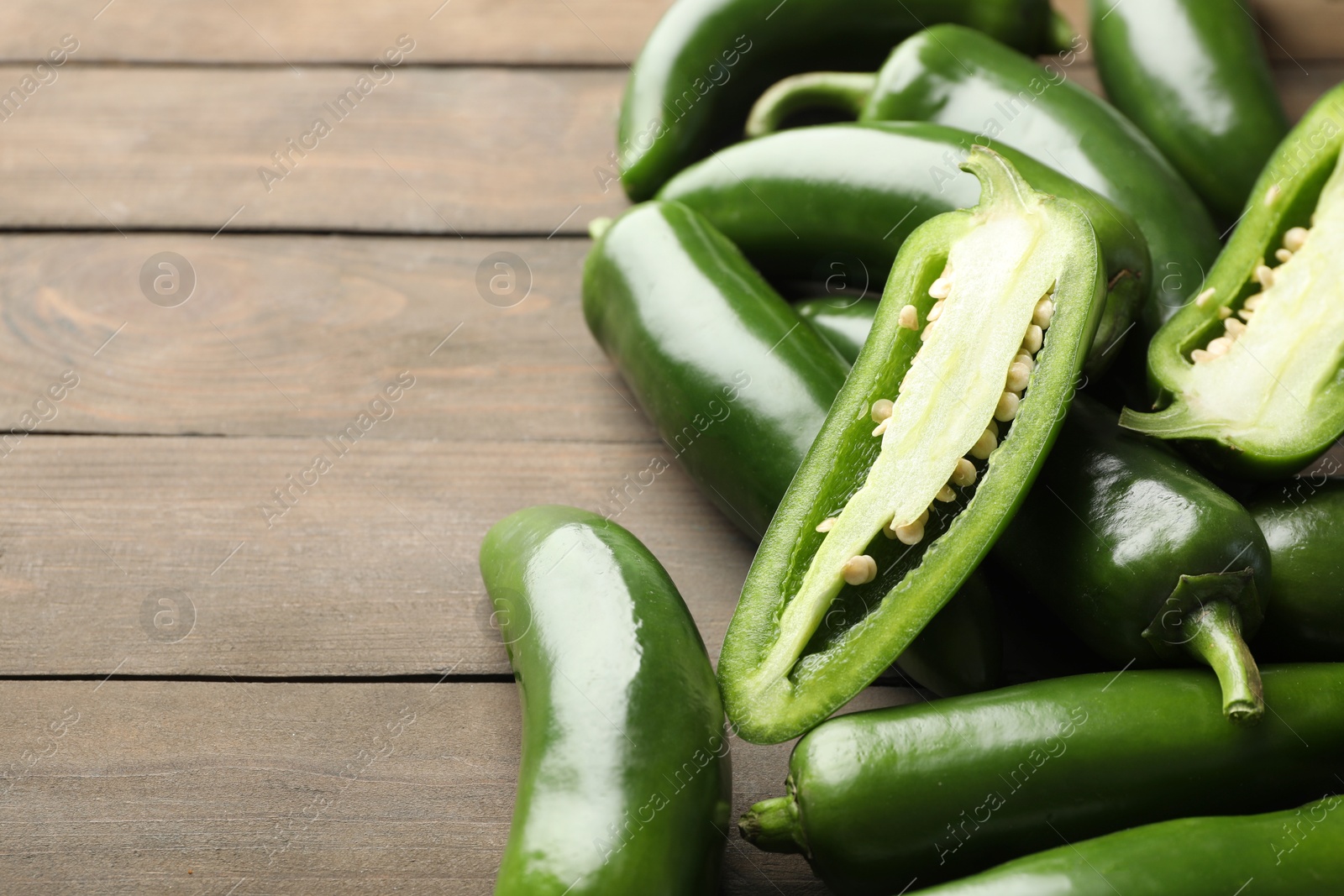 Photo of Fresh jalapeno peppers on wooden table, closeup. Space for text