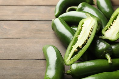 Photo of Fresh jalapeno peppers on wooden table, closeup. Space for text