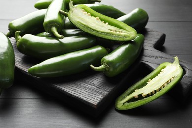 Photo of Fresh jalapeno peppers on black wooden table, closeup