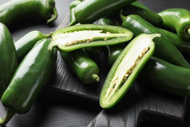 Photo of Fresh jalapeno peppers on black wooden table, closeup