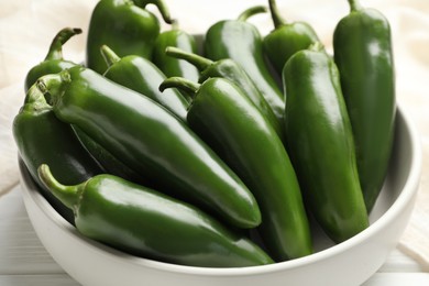 Photo of Fresh jalapeno peppers in bowl on white table, closeup