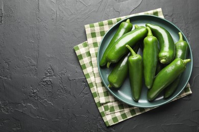 Photo of Fresh jalapeno peppers on black textured table, top view. Space for text