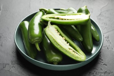 Photo of Fresh jalapeno peppers on black textured table, closeup