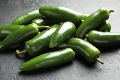 Photo of Fresh jalapeno peppers on black textured table, closeup