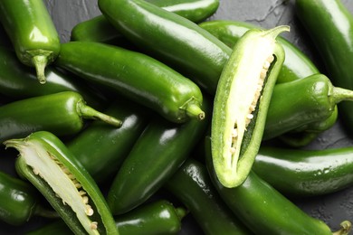 Photo of Fresh jalapeno peppers on black table, closeup