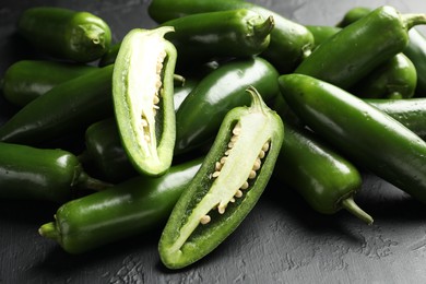 Photo of Fresh jalapeno peppers on black textured table, closeup