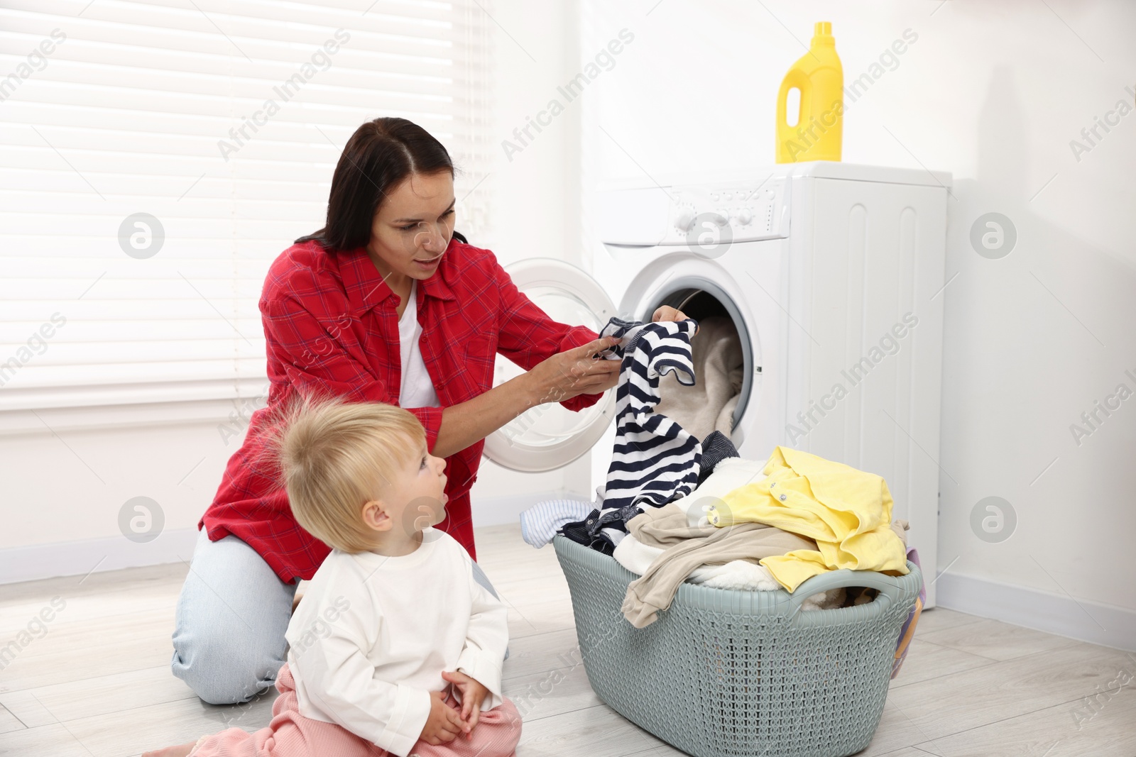Photo of Housewife with her baby doing laundry at home
