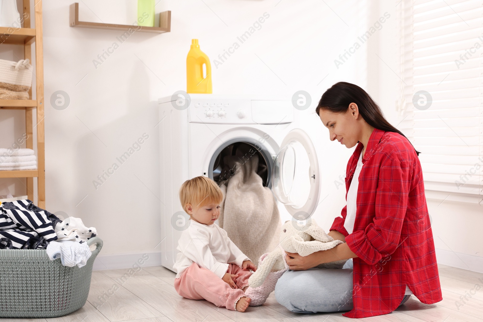 Photo of Housewife with her baby doing laundry at home