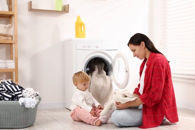 Photo of Housewife with her baby doing laundry at home