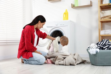Photo of Housewife with her baby doing laundry at home