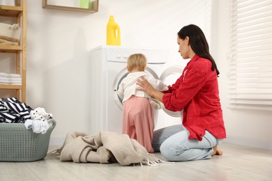 Photo of Housewife with her baby doing laundry at home