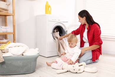 Photo of Housewife with her baby doing laundry at home