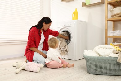 Photo of Housewife with her baby doing laundry at home