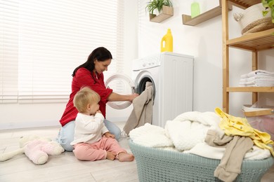 Photo of Housewife with her baby doing laundry at home