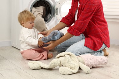 Photo of Housewife with her baby doing laundry at home, closeup