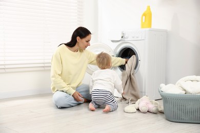 Photo of Housewife with her baby doing laundry at home