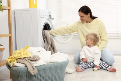 Photo of Housewife with her baby doing laundry at home